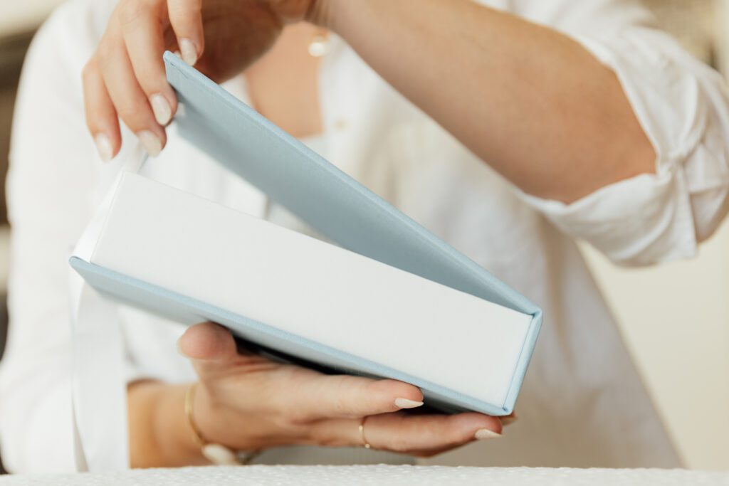 close up of hands opening a blue and white wedding album